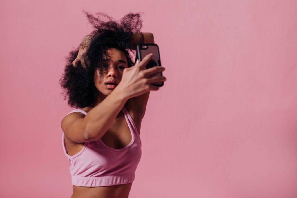 woman takes a photo in front of a pink background