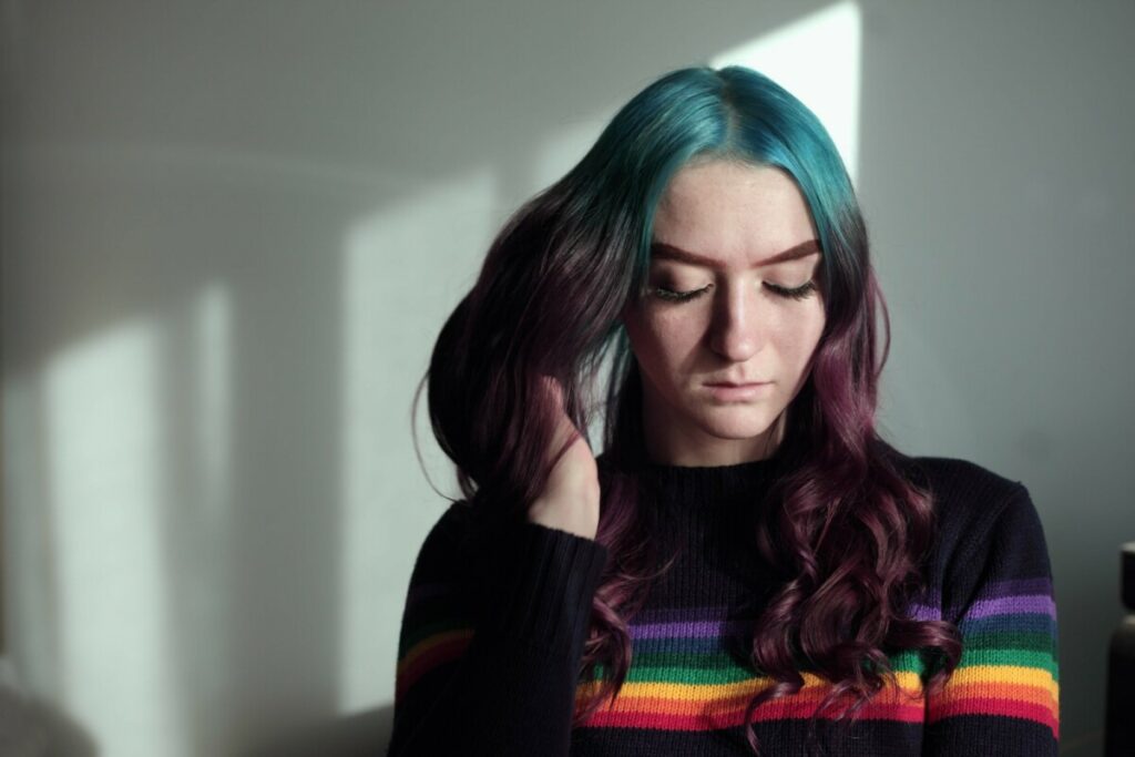 woman with blue and purple hair wearing a rainbow sweater