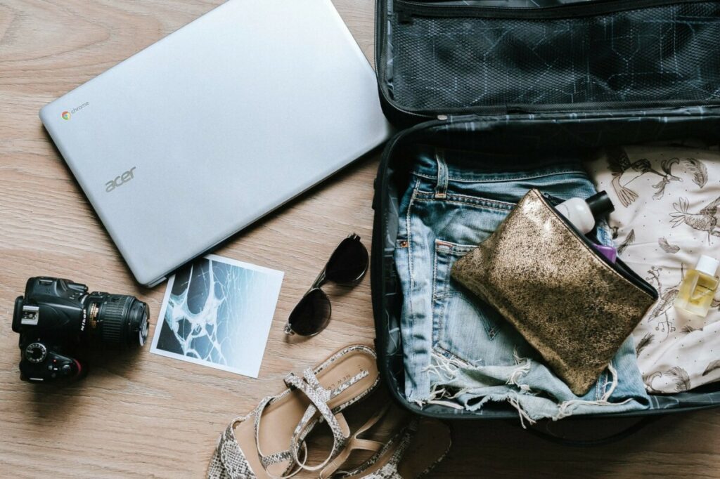 overhead shot of an open suitcase with travel items like a camera and sunglasses