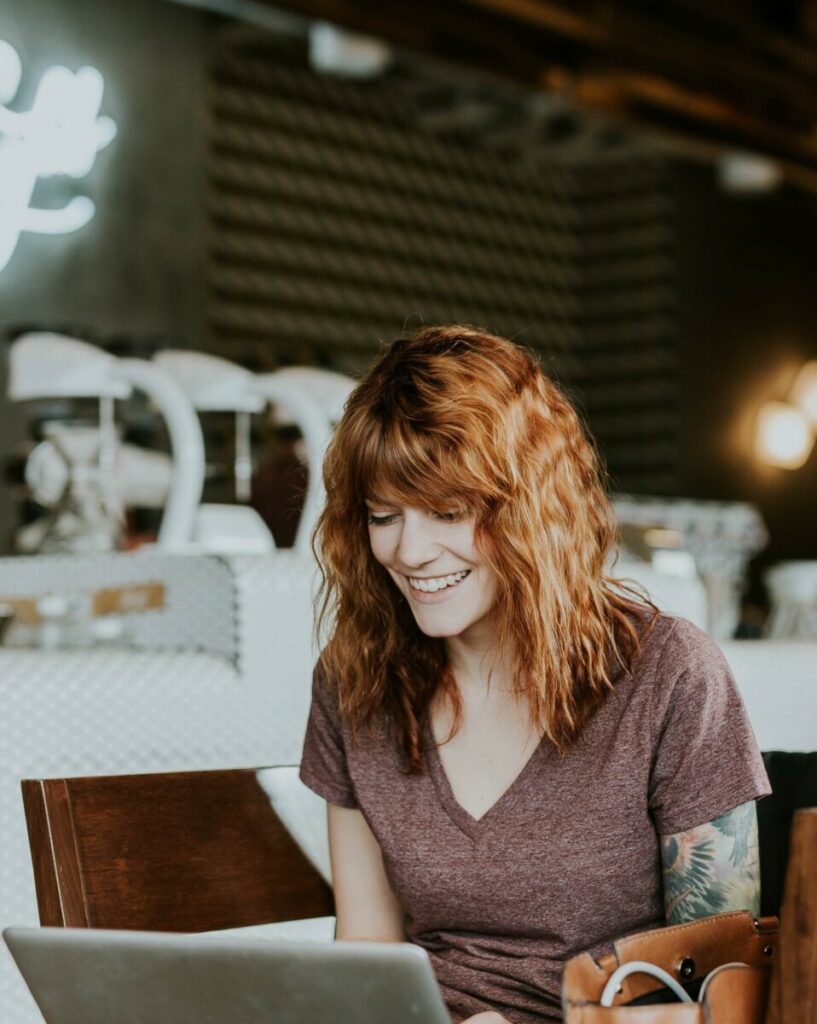 woman laughing as she types on her laptop during a business photoshoot