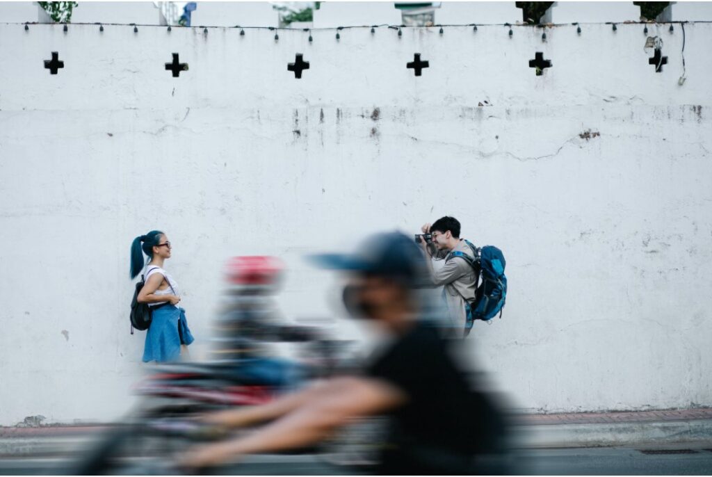 couple staking pictures in front of a wall